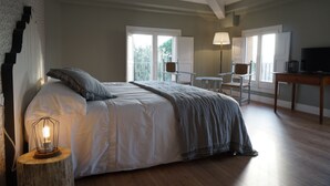 A bedroom with a large bed, a bedside table with a lamp, a chair, and a TV. - Can Ribalta Hotel Gastronòmic (Sant Antoni de Vilamajor)
