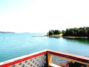 A waterfront view with a wooden deck and a clear sky.