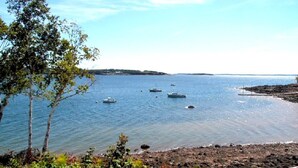 Un paysage côtier avec une eau calme, des bateaux et une côte rocheuse.
