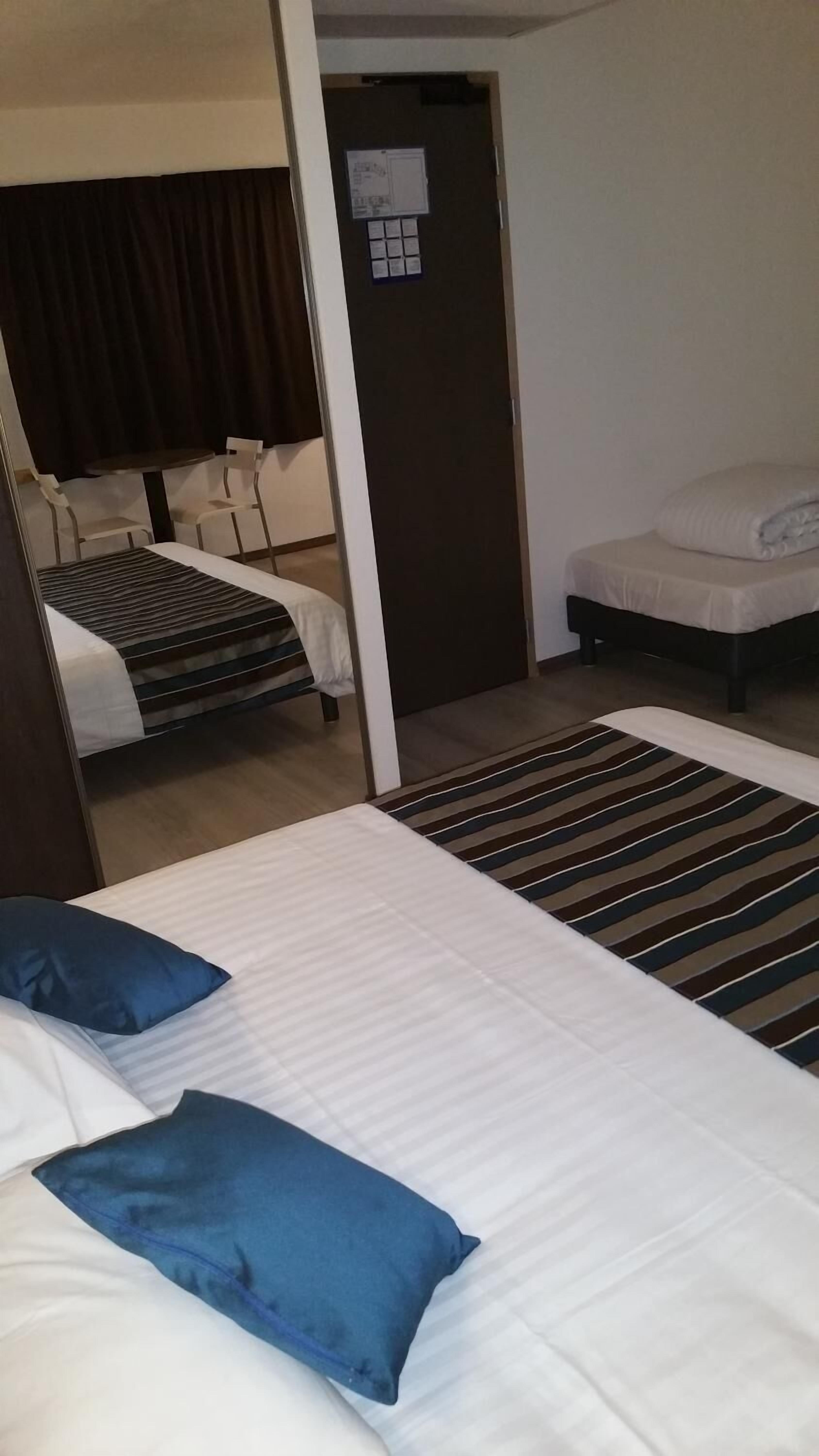 Una habitación de hotel con dos camas, una mesita pequeña y una silla.