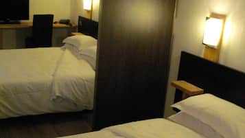 Habitación de hotel con dos camas, un escritorio con computadora y televisor montado en la pared.