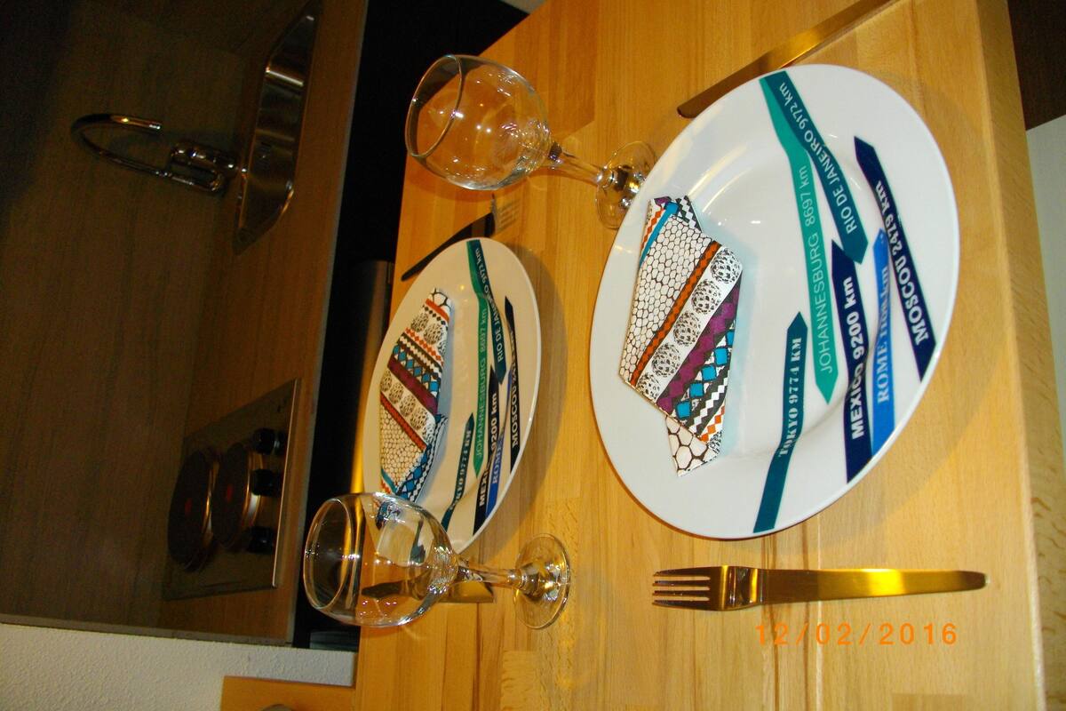A dining table with plates, cutlery, and a wine glass.