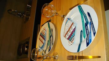 A dining table with plates, cutlery, and a wine glass.