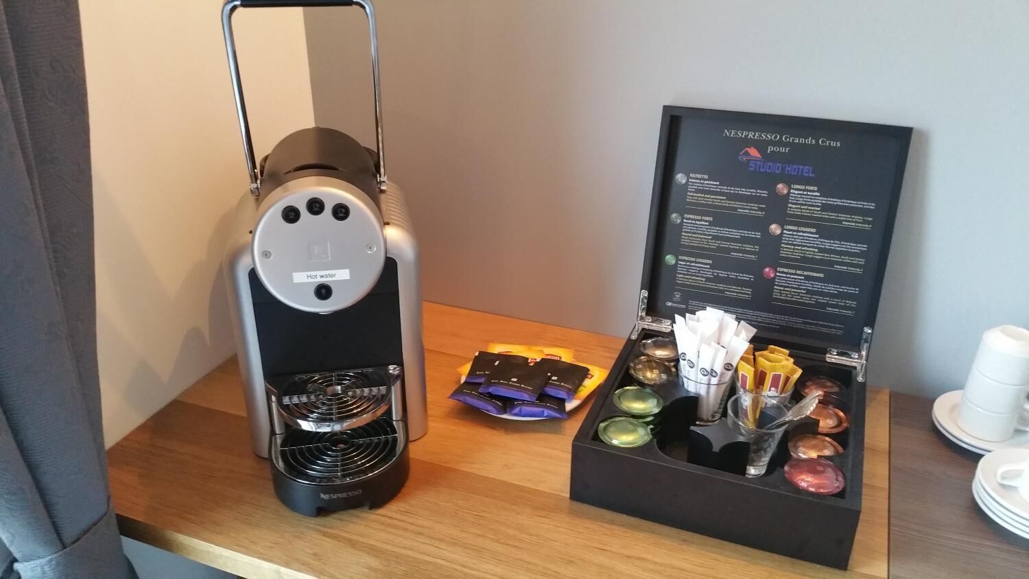 Una cafetera Nespresso Grand's Crus, una caja con cápsulas de café y una cuchara.