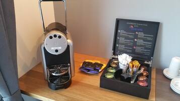 A Nespresso Grand's Crus coffee machine and a box containing coffee pods and a spoon.