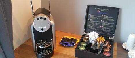 A Nespresso Grand's Crus coffee machine and a box containing coffee pods and a spoon.