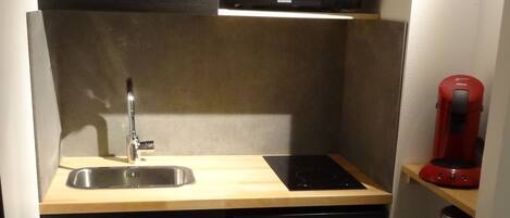 A compact kitchen with a microwave, sink, and a coffee maker.