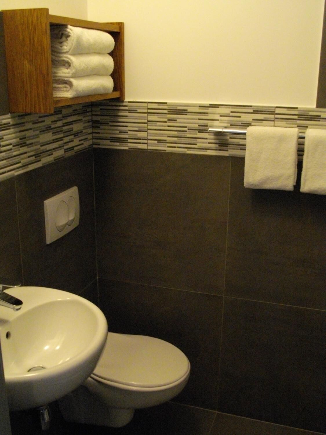 Ein Badezimmer mit Waschbecken, Toilette und Handtuchhalter mit gefalteten Handtüchern.
