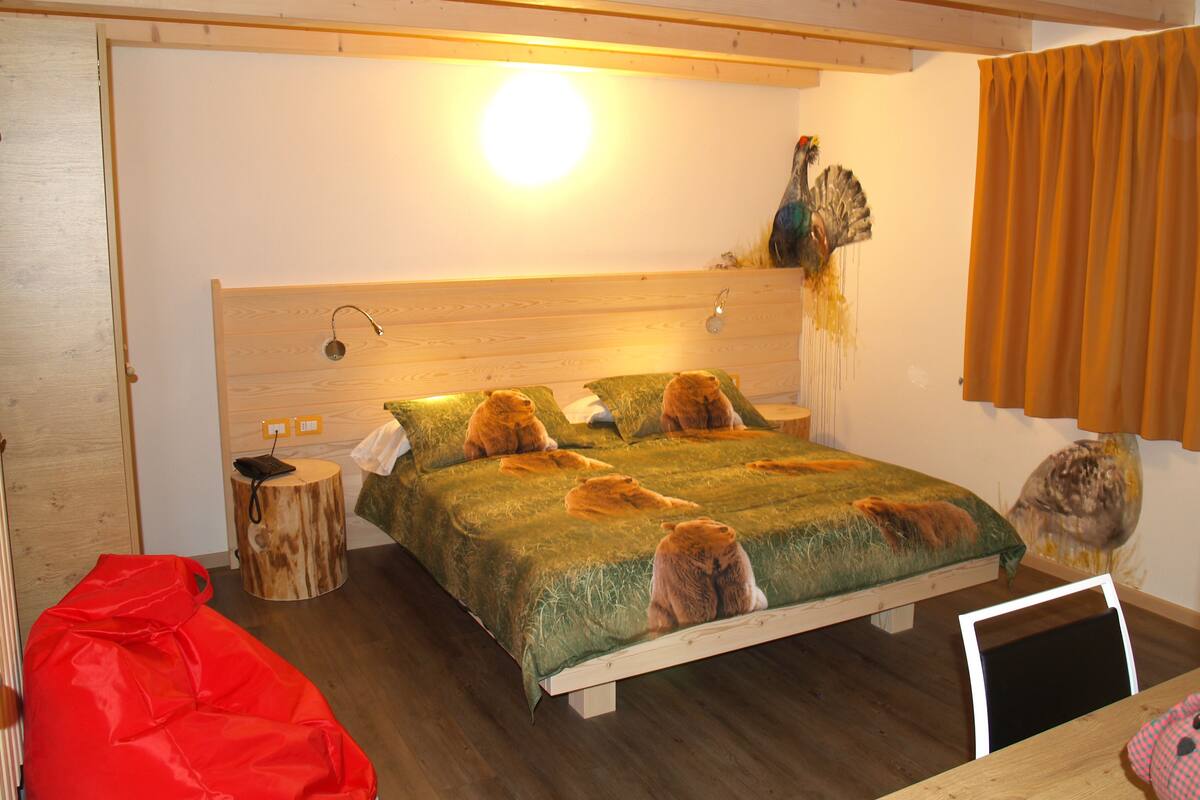 Une chambre à coucher avec un lit, une table de chevet, une lampe, un sac rouge et une tête de lit en bois.