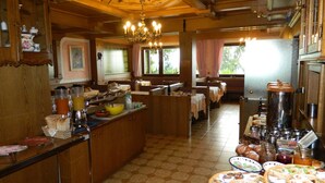 Un restaurant doté d’un îlot central, de meubles en bois et d’un lustre.