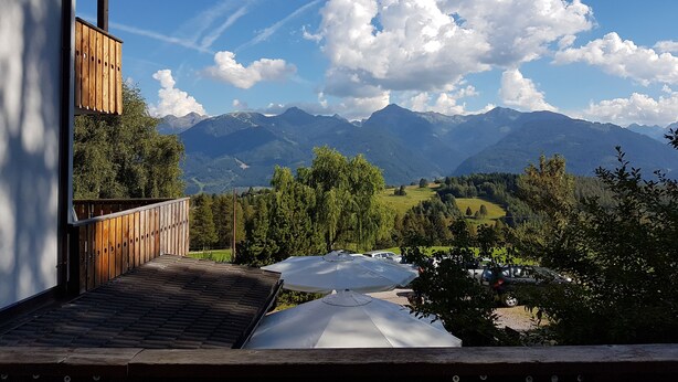 Une terrasse en bois offrant une vue sur les montagnes et une rivière.