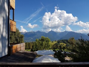 Une terrasse en bois offrant une vue sur les montagnes et une rivière.