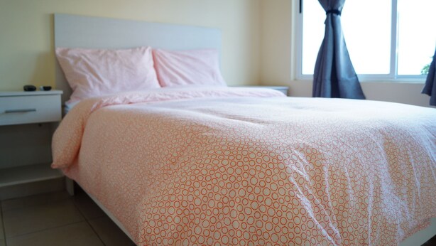 A bedroom with a bed, nightstand, and window with curtains.
