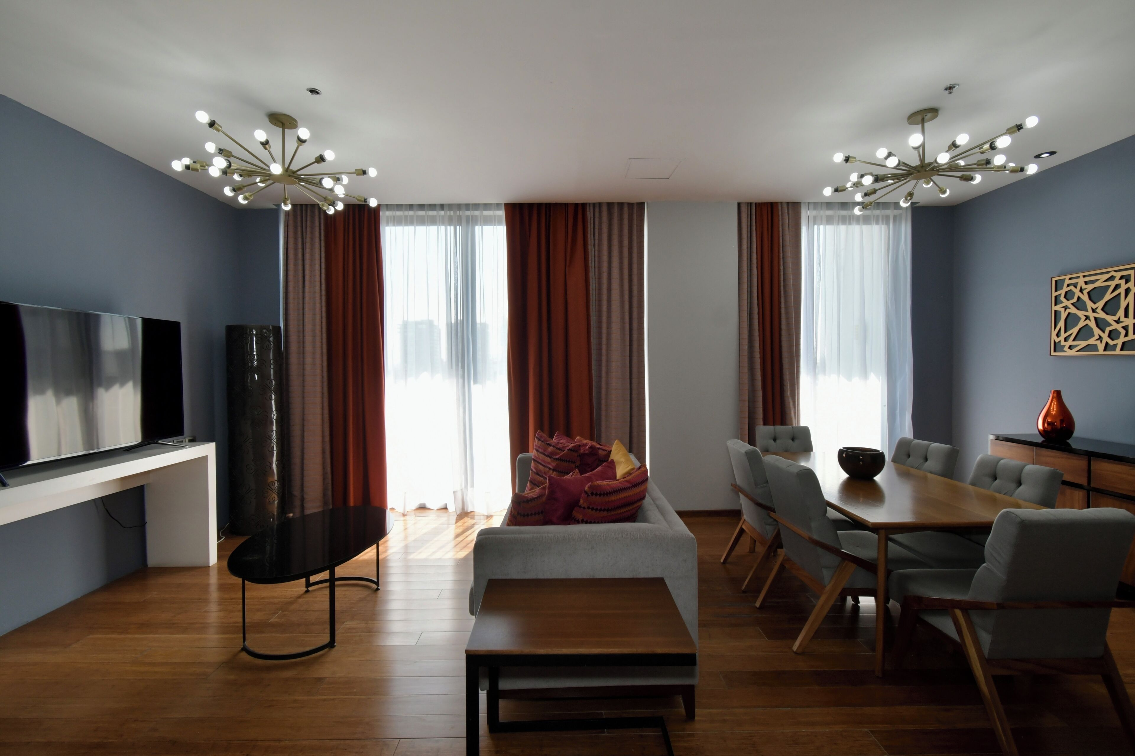 Una sala moderna con televisor de pantalla plana, un sofá, una mesa de comedor con sillas y una mesa de centro.