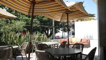 Un espacio al aire libre con sombrillas a rayas, muebles de mimbre y un sofá con cojines.