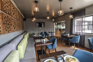 Un restaurante con zona de bar, asientos de respaldo alto e iluminación colgante.