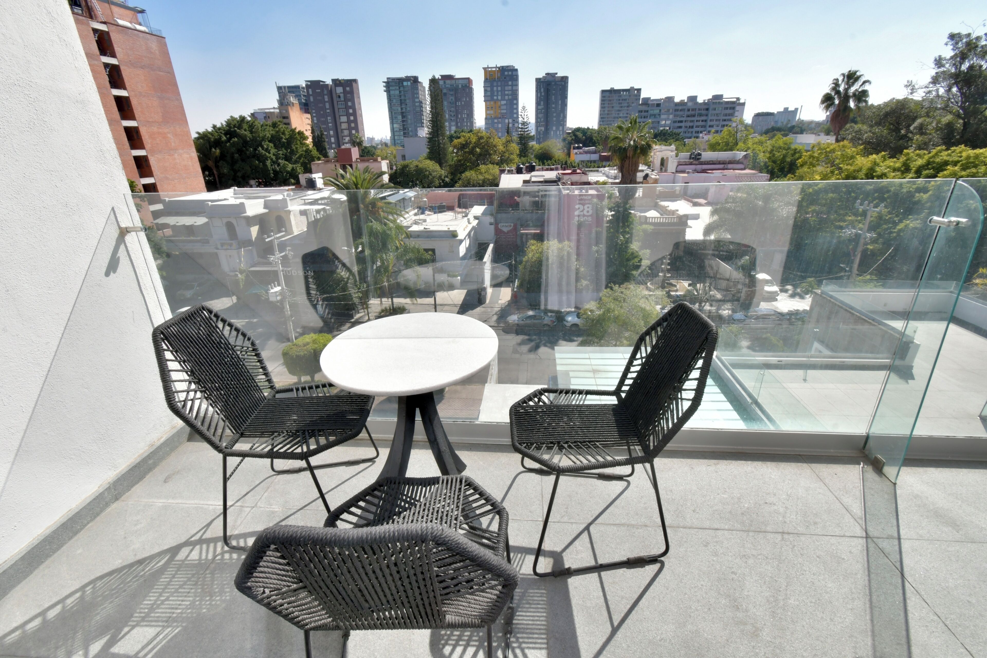 A balcony with a glass railing, a round table, and two chairs.