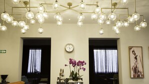 A lobby with a modern chandelier, a clock, and a statue. - Hotel Love It CAS Consulate (Guadalajara)