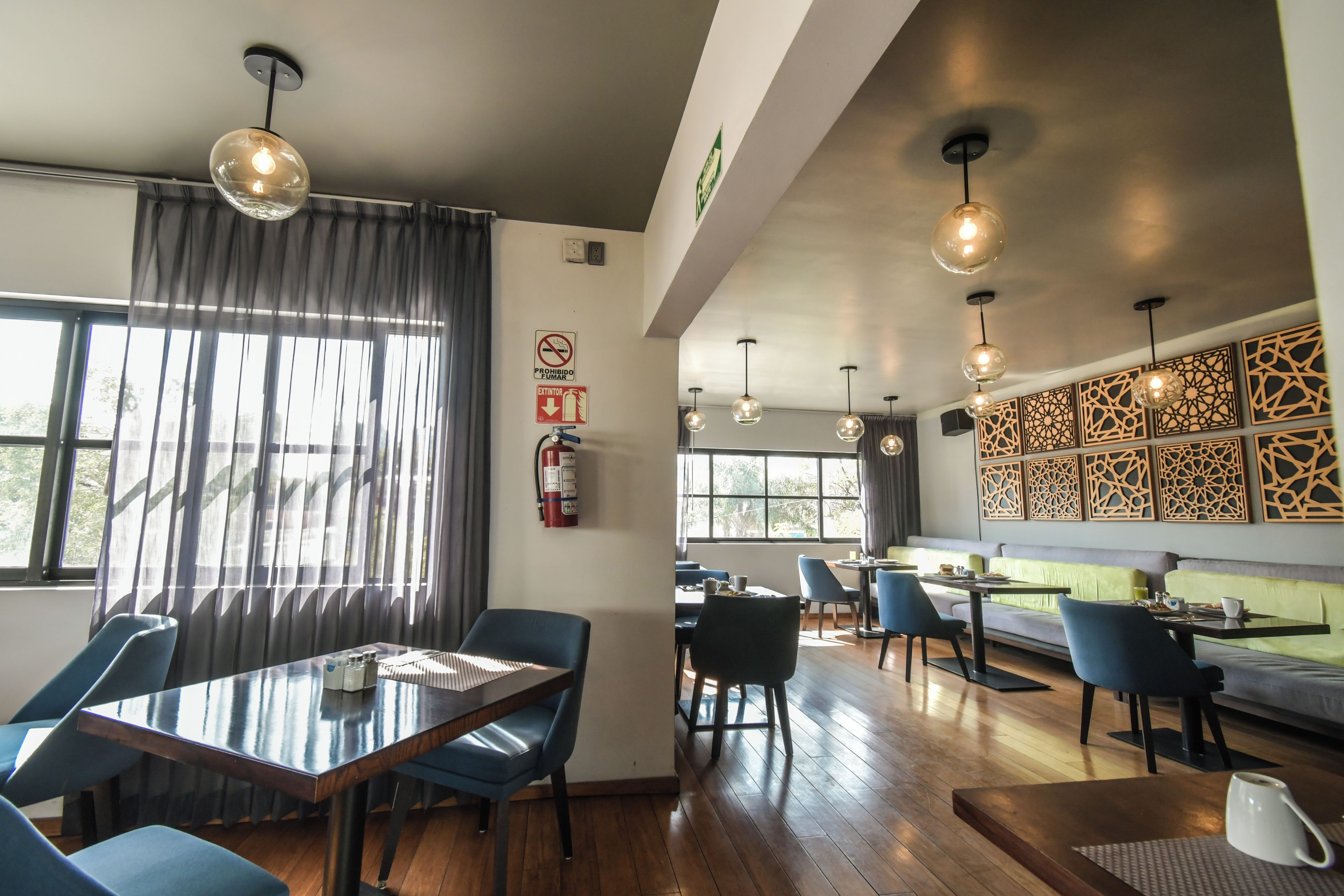 A modern dining area with a glass table, blue chairs, and pendant lighting.