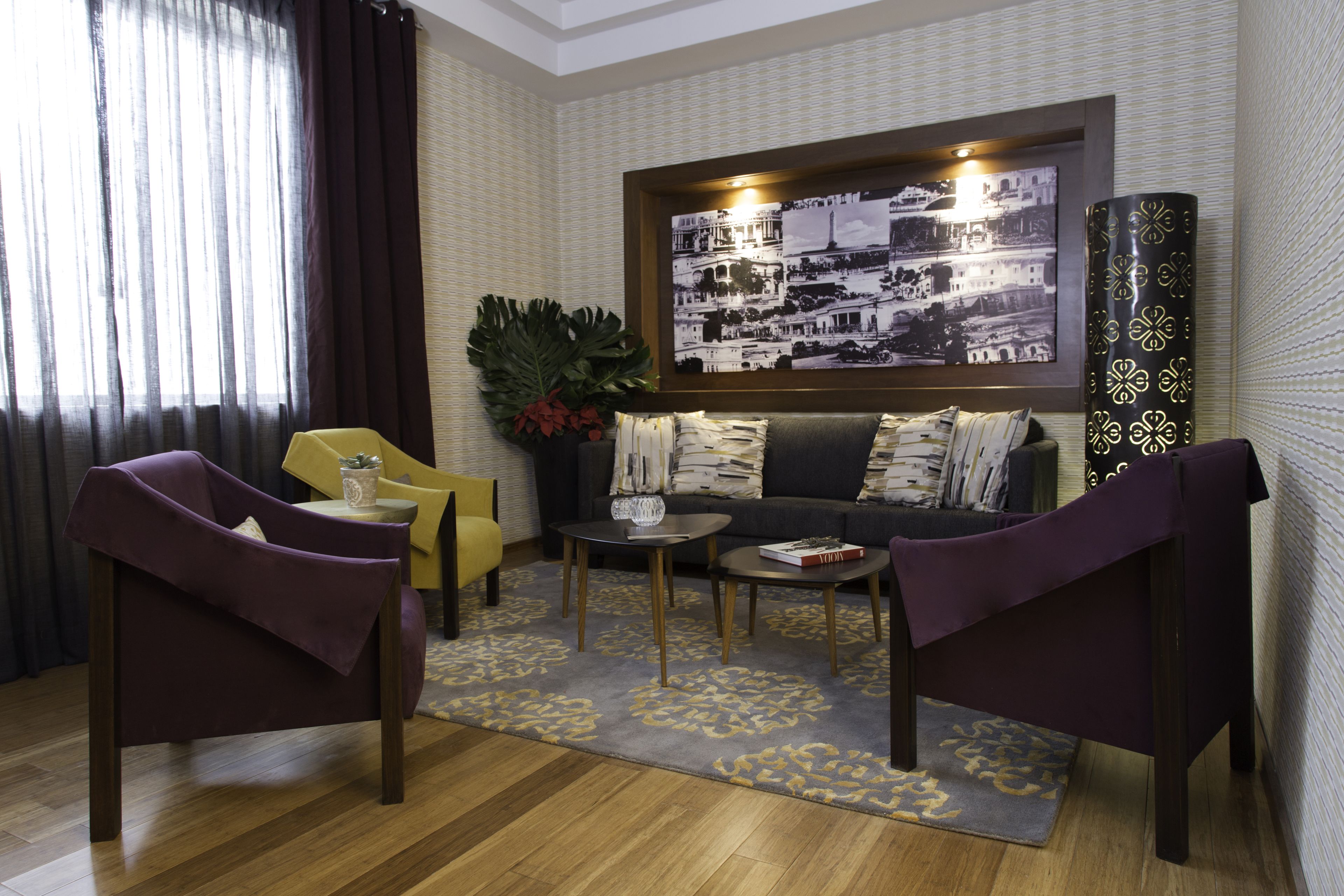 A living room with a sofa, two armchairs, a coffee table, and a large framed picture on the wall.
