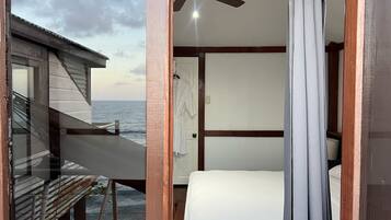 Una habitación con cama, ventilador de techo y vista al océano.