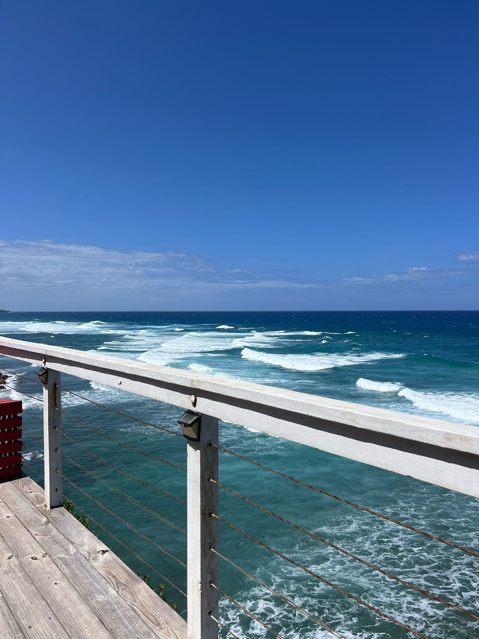 A wooden deck with a railing overlooking the ocean.