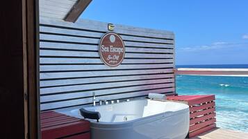 Een houten terras met een jacuzzi en een bord waarop staat: Sea Escape Sea Cliff.
