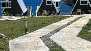 Una hilera de cabañas modernas con techos triangulares y una vista despejada del océano.