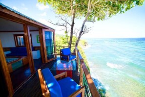 A wooden deck with blue chairs overlooking a clear blue sea. - Sea Cliff Resort (Long Bay)