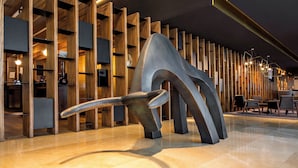 Un interior moderno con una escultura metálica única, paneles de madera y un suelo pulido.