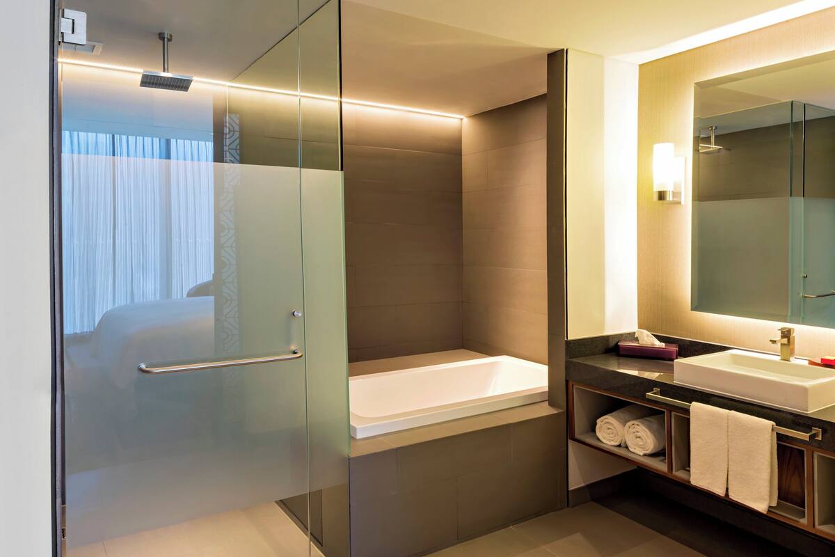 Une salle de bain moderne avec une douche à parois de verre, une baignoire blanche et un meuble-lavabo avec un miroir.
