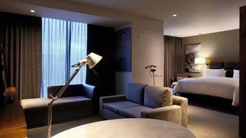 Ein Hotelzimmer mit einem Bett, einer Couch, einem Schreibtisch und einer Lampe.