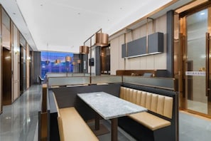 A modern interior with a seating area featuring a marble table and cushioned benches. - Vienna Classic Hotel(Dongguan Chang'an West Railway Station Modern City Store) (Dongguan)