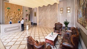 Eine Lobby mit Empfangstresen, Ledersofas, einem Couchtisch und einer großen Kronleuchter.
