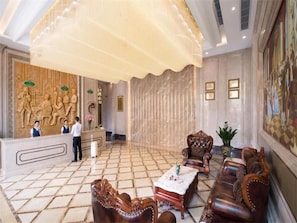 A lobby with a reception desk, leather sofas, a coffee table, and a large chandelier. - Vienna Classic Hotel(Dongguan Chang'an West Railway Station Modern City Store) (Dongguan)