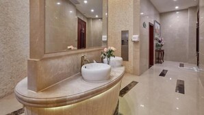 Ein modernes Badezimmer mit einem gebogenen Waschtisch, einem großen Spiegel und einem wandmontierten Waschbecken.