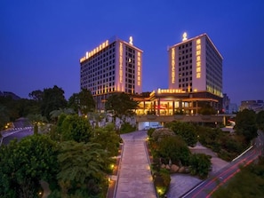 Un hôtel doté de deux tours imposantes, d’un jardin aménagé et d’une entrée bien éclairée.