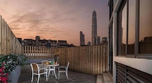 A rooftop terrace with a table and chairs, a wooden fence, and a city skyline in the background. - Viennahotel Shenzhen Exibition Center (Shenzhen)
