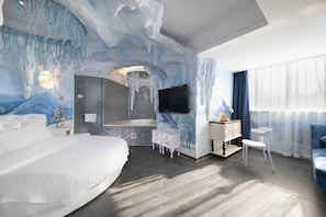 Une chambre d’hôtel moderne dotée d’un grand lit, d’une salle de bain avec douche, d’une coiffeuse avec miroir et d’un téléviseur fixé au mur.
