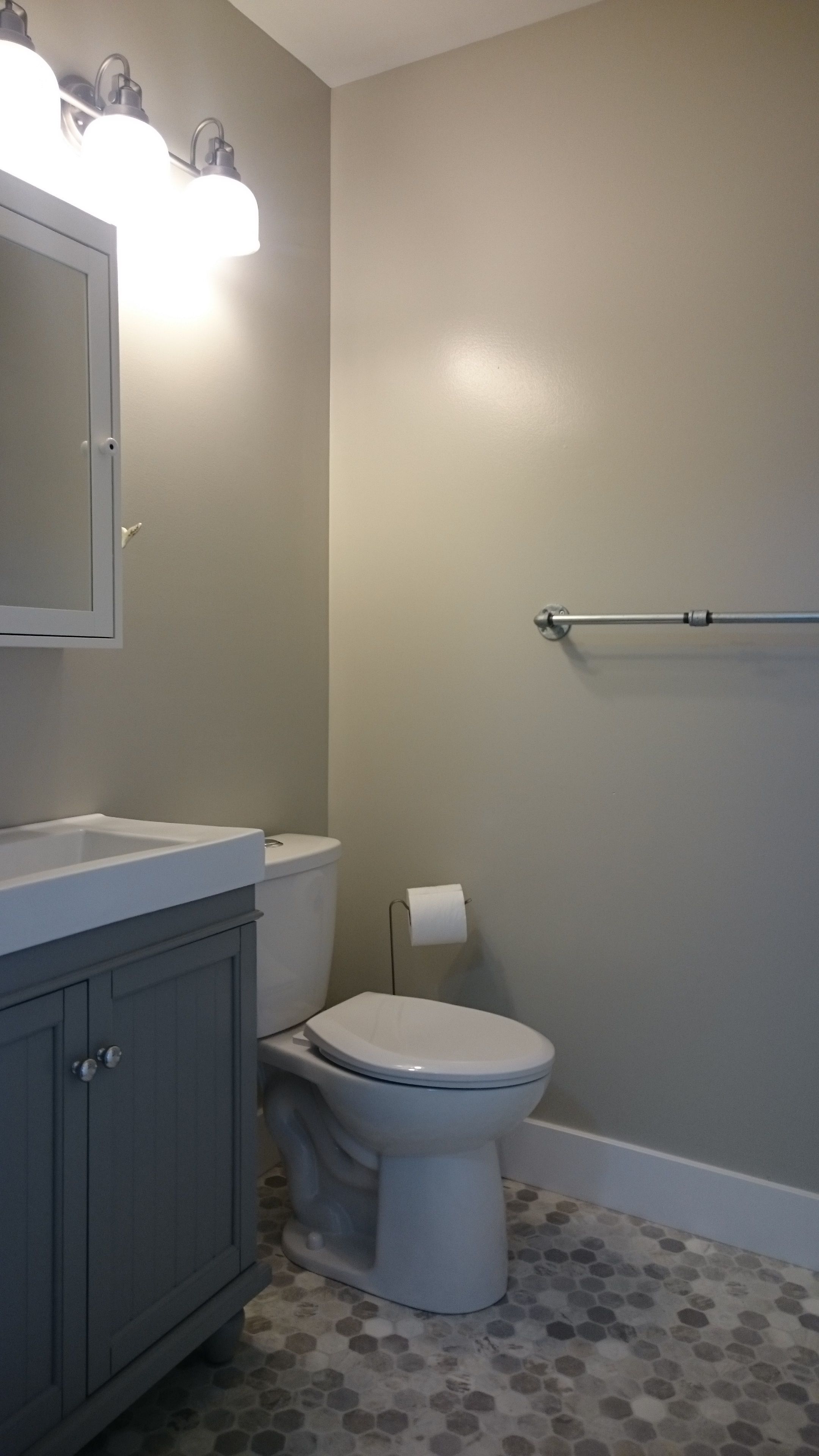 A bathroom with a toilet, a sink with a mirror, and a towel rack.