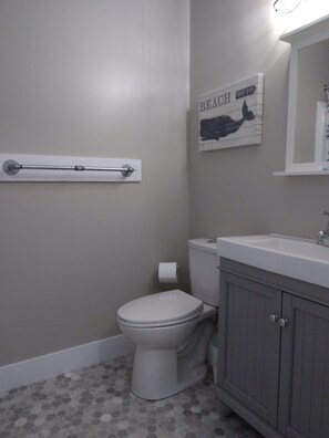 Une salle de bain équipée de toilettes, d’un lavabo et d’un porte-serviettes fixé au mur.