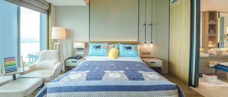 Habitación de hotel moderna con una cama grande, un escritorio con lámpara y vistas a una masa de agua.