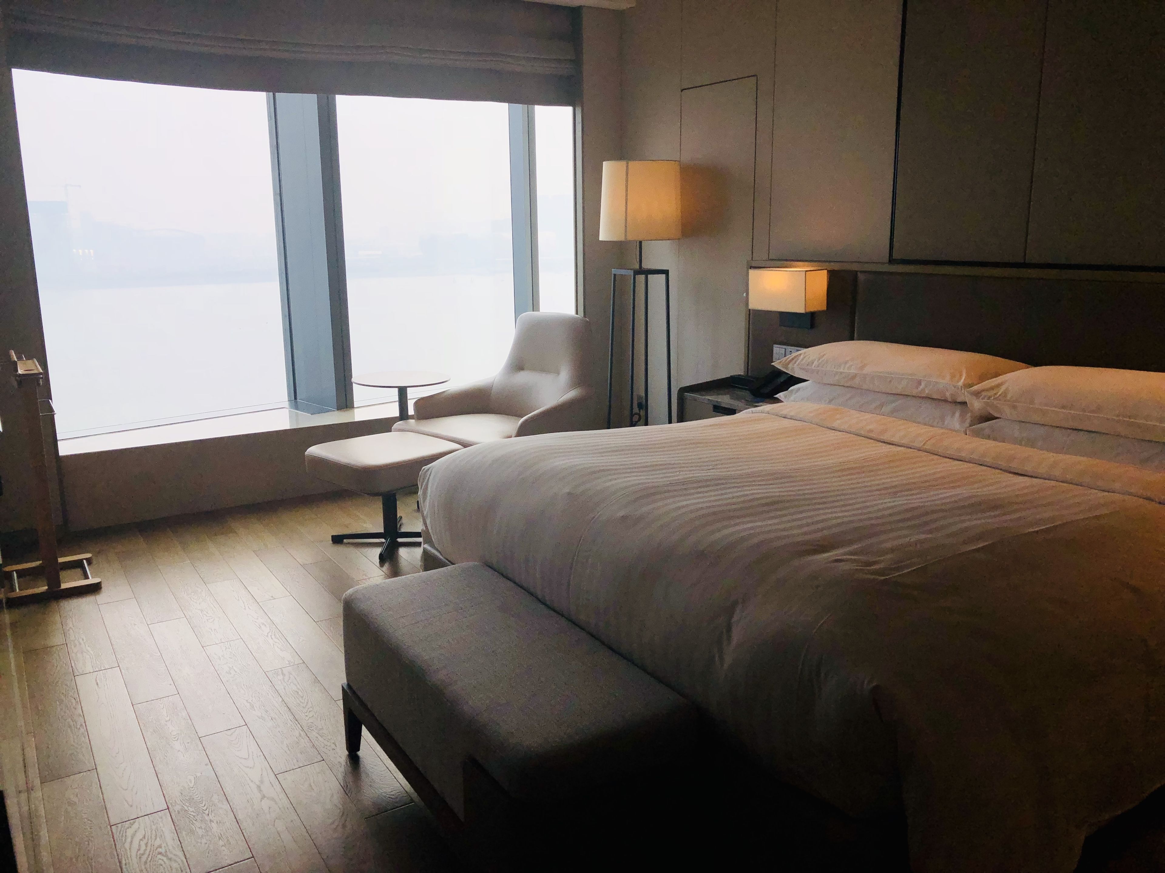 Habitación de hotel con una cama grande, una silla, una mesita y una lámpara.
