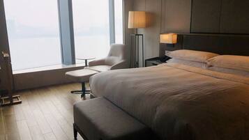 Habitación de hotel con una cama grande, una silla, una mesita y una lámpara.