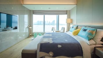 A modern hotel room with a large bed, a TV, a view of the city, and a balcony.