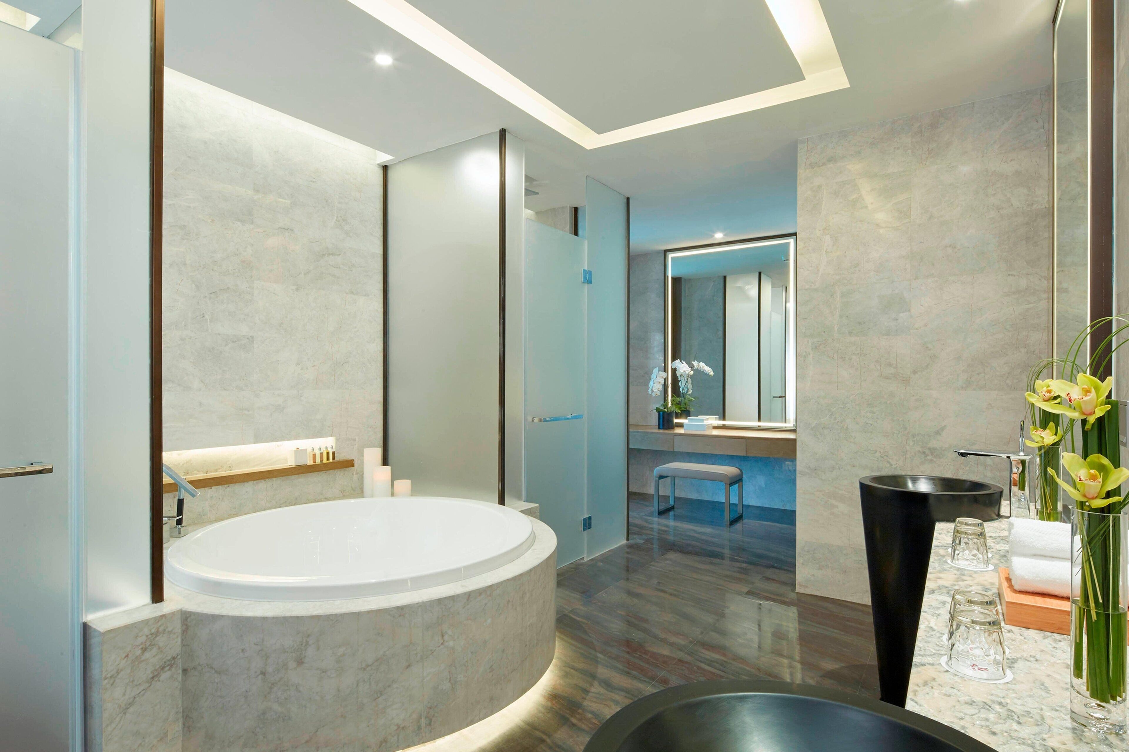 Un baño moderno con una bañera grande, un lavabo negro y un espejo.