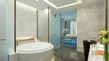 Un baño moderno con una bañera grande, un lavabo negro y un espejo.
