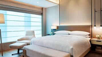 Una habitación de hotel moderna con una cama grande, una zona de estar y un escritorio con una lámpara.