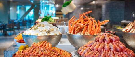 Un bufé con diversas opciones de mariscos, incluyendo camarones, patas de cangrejo y langosta.