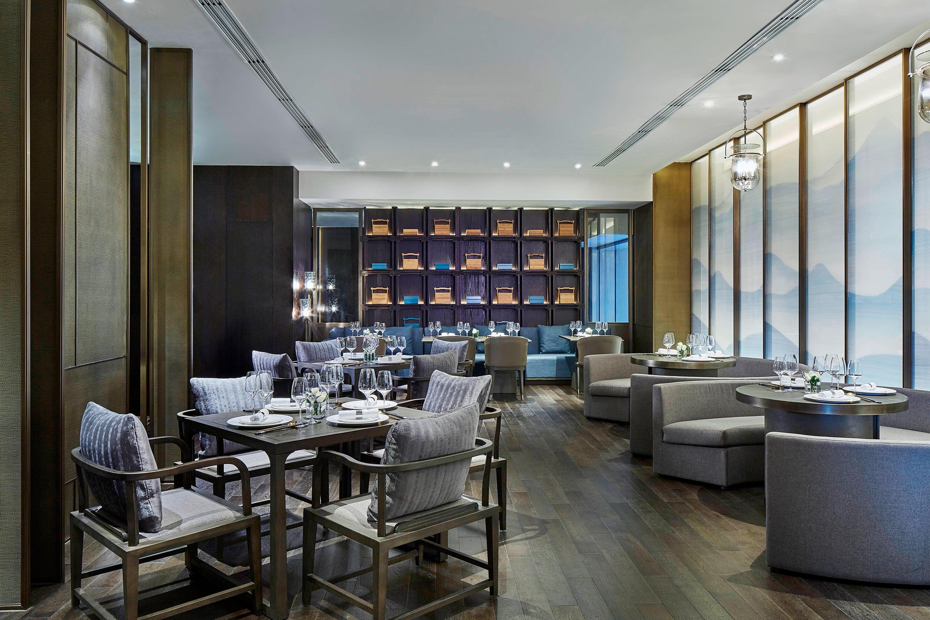 Un restaurante moderno con muebles de madera, una zona de bar y una pared con premios.